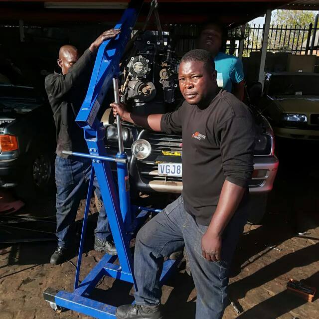 Our mechanic with an engine hoist in the workshop